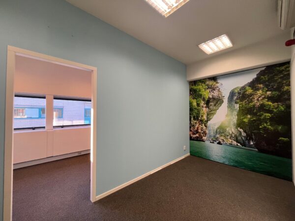 Klein leeg kantoor in Leidse Rijn met een muurposter van een tropisch landschap met rotsen en water.